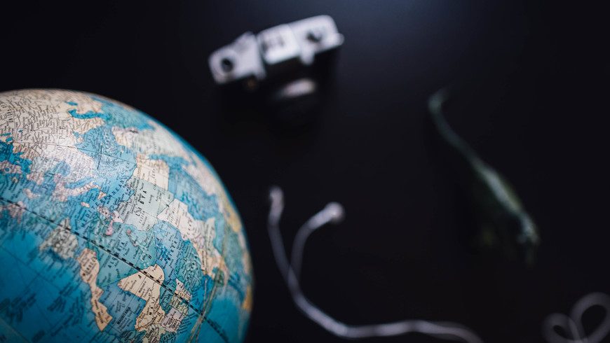 Vintage globe and camera sitting on black table.