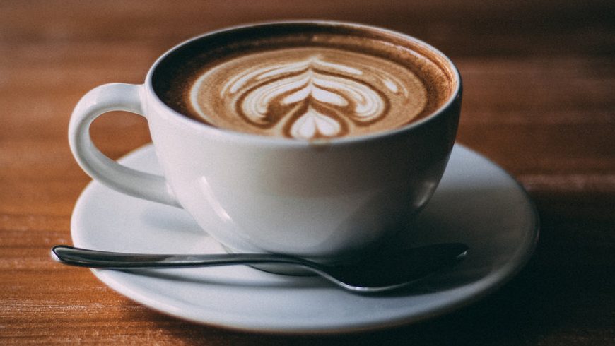 Neat cup of coffee and spoon with intricate foam design