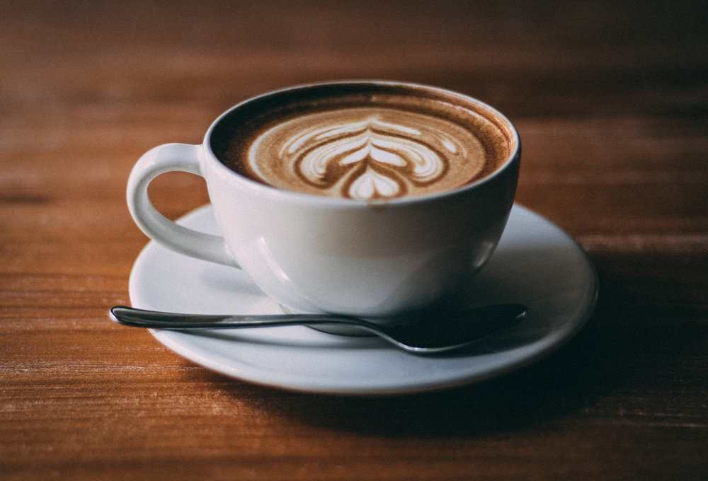 Neat cup of coffee and spoon with intricate foam design